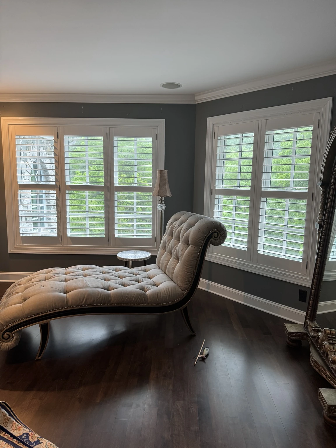 White plantation shutters and a chaise in a finished room